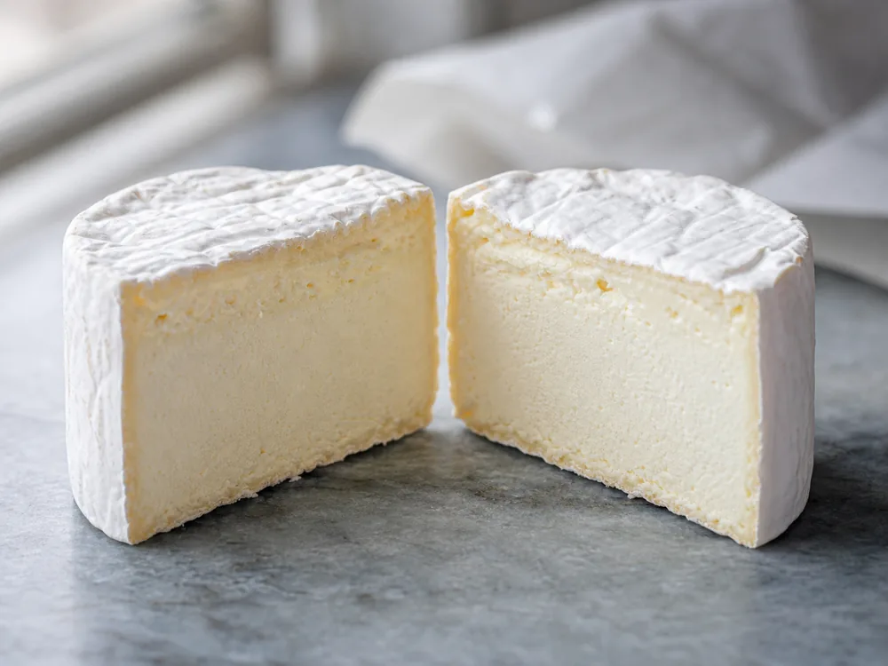 Cut Saint-Andre round showing a dense creamy center beneath white rind