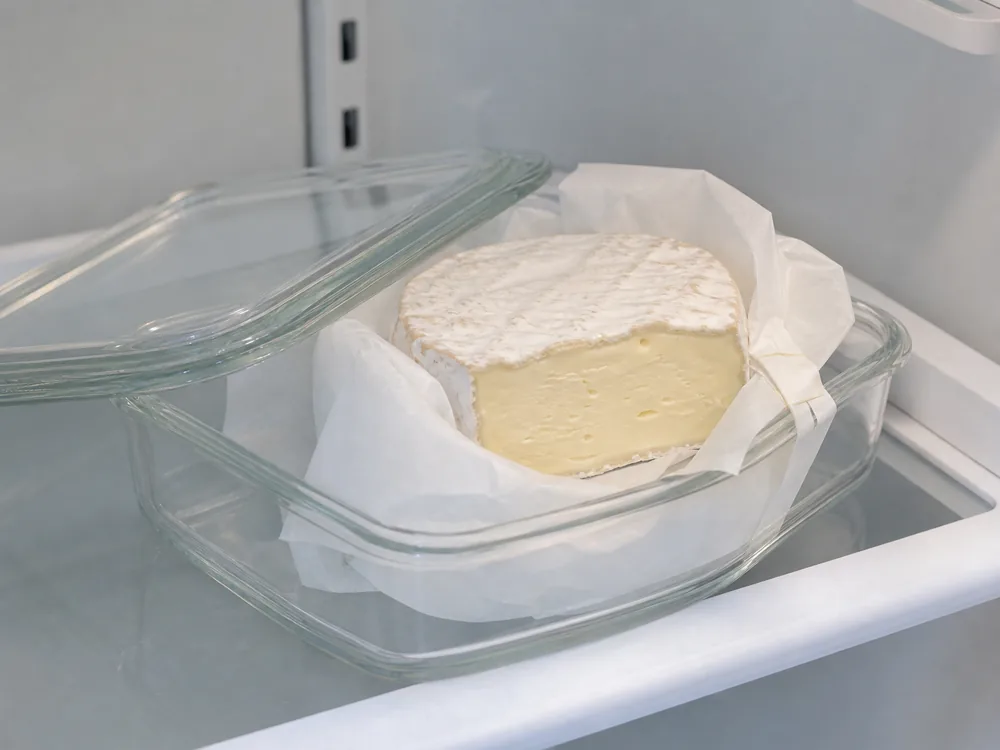 Cut Saint-Andre loosely wrapped in cheese paper inside an ajar glass container - Saint-Andre | KnowTheCheese