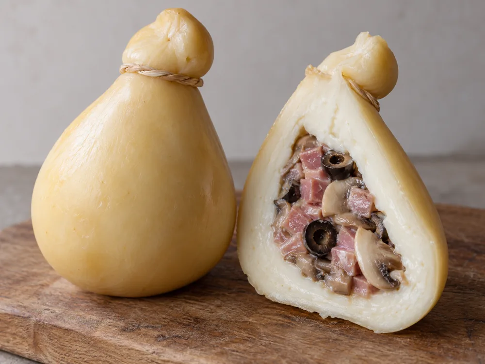 Pear-shaped scamorza cut in half to show a pocket filled with diced ham, olives and mushrooms - Scamorza cheese | KnowTheCheese