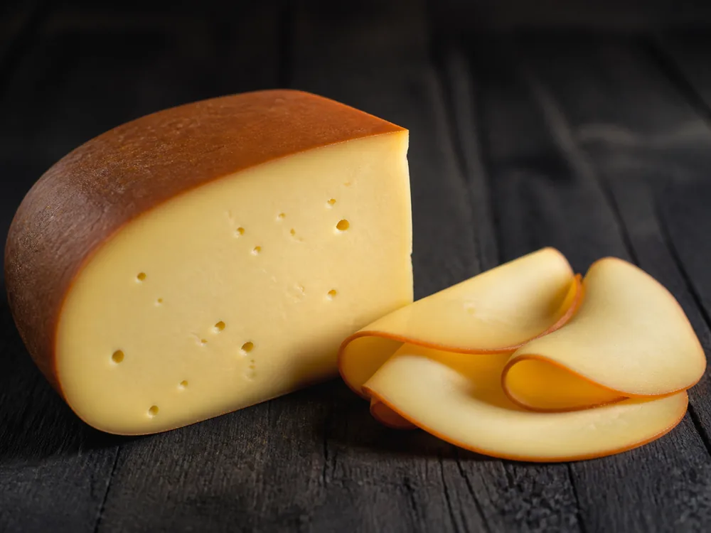 Smoked Gouda wedge with a pale smooth paste and thin brown exterior - Smoked Gouda | KnowTheCheese