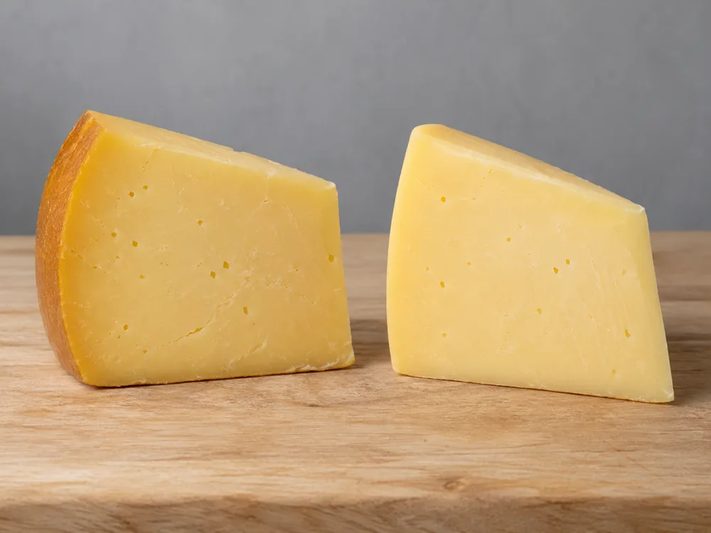 Two Gouda wedges side by side, the left with a darker brown outer edge and the right with its colour running evenly to the outside - Smoked Gouda | KnowTheCheese