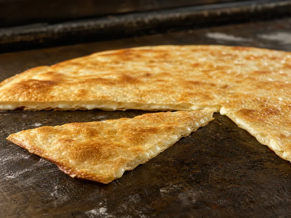 Thin focaccia di Recco cut open to show a delicate Stracchino filling