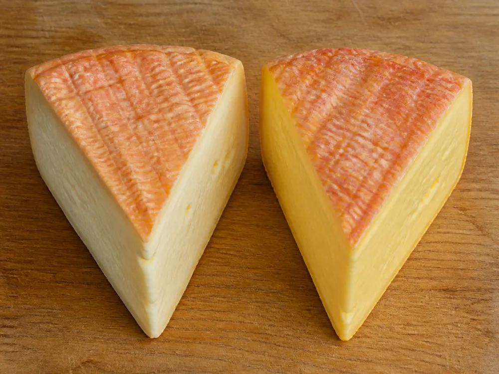 Two wedges of the same washed-rind cheese with paler and more golden pastes - Tamie | KnowTheCheese