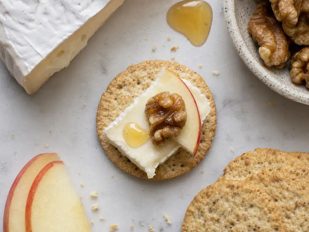 Single balanced cheese bite with cracker soft cheese apple nut and honey - The Perfect Bite | KnowTheCheese