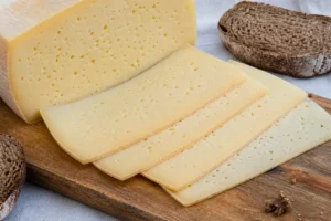Sliced Tilsiter with pale paste and many small holes - Tilsiter cheese | KnowTheCheese