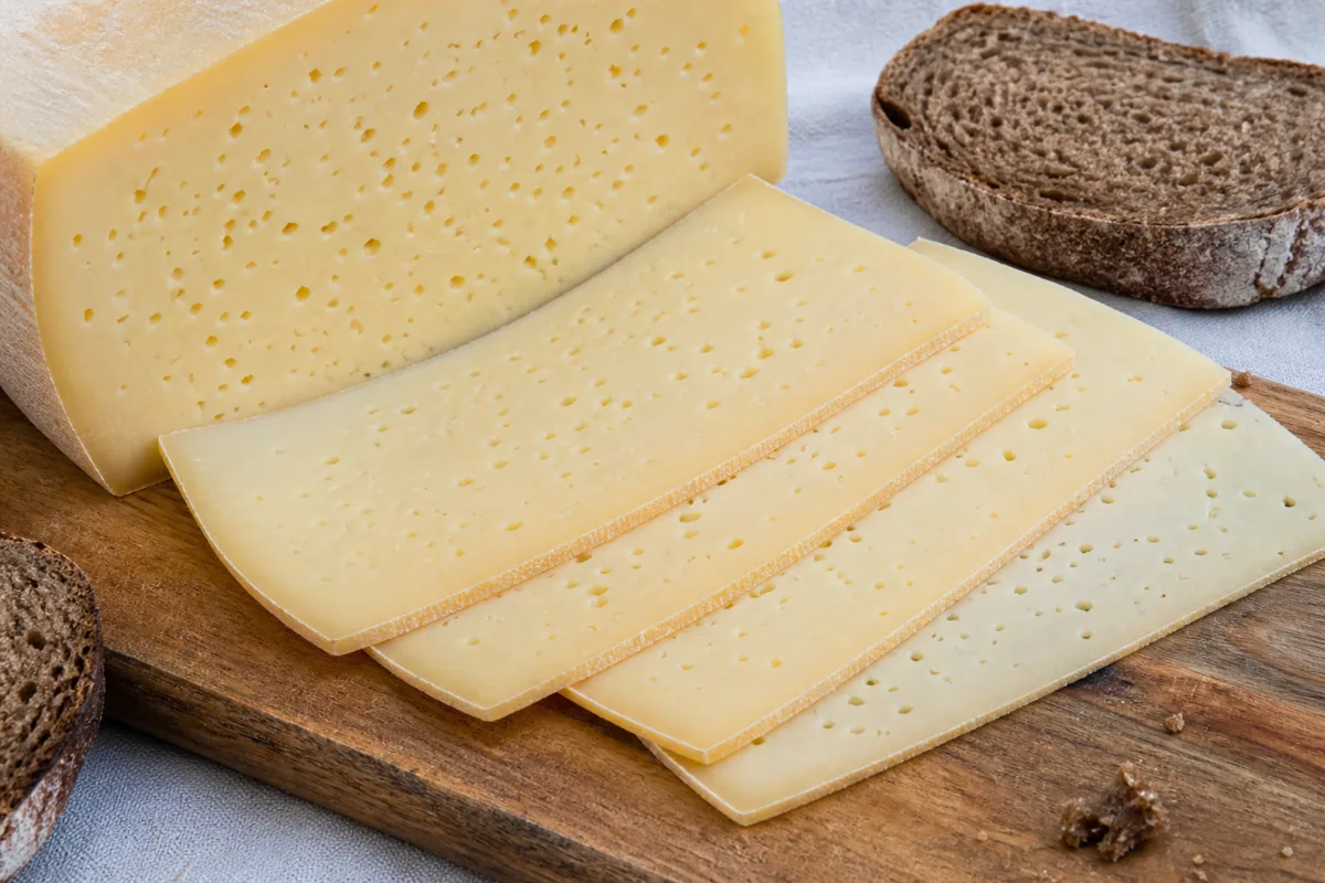 Sliced Tilsiter with pale paste and many small holes - Tilsiter cheese | KnowTheCheese