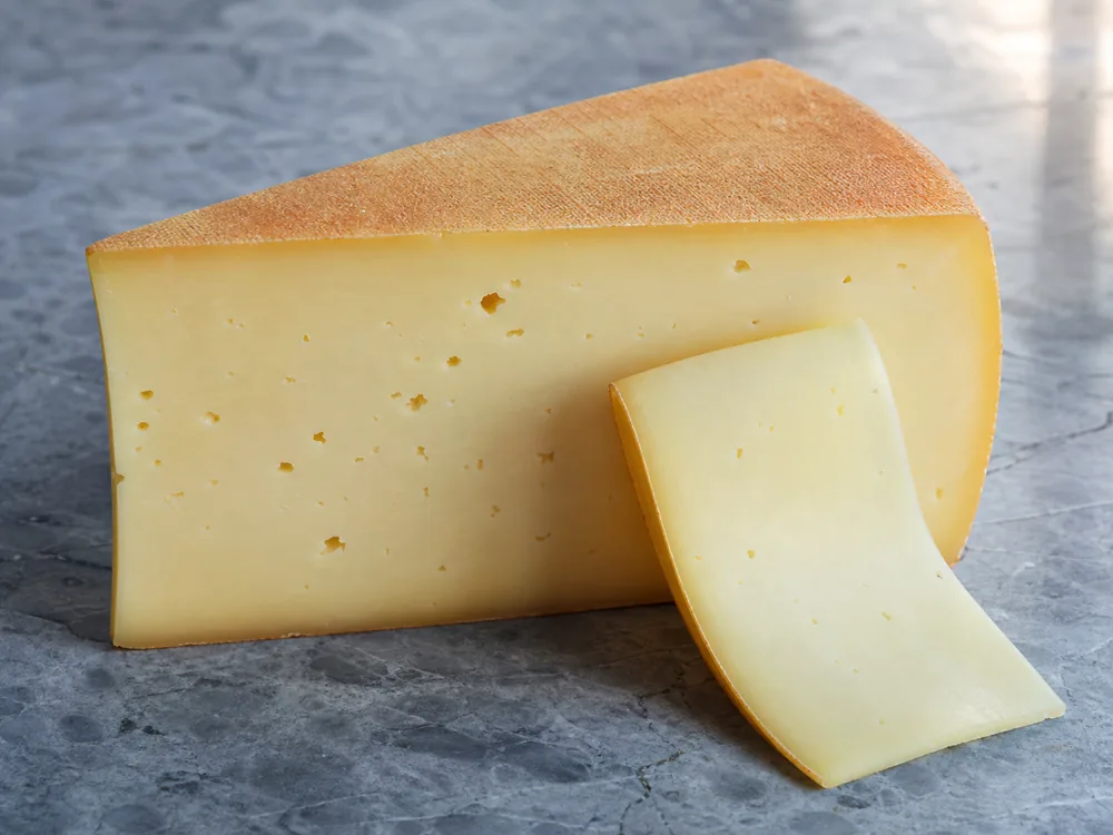 Tilsiter wedge showing its washed rind and small-eyed supple paste - Tilsiter | KnowTheCheese