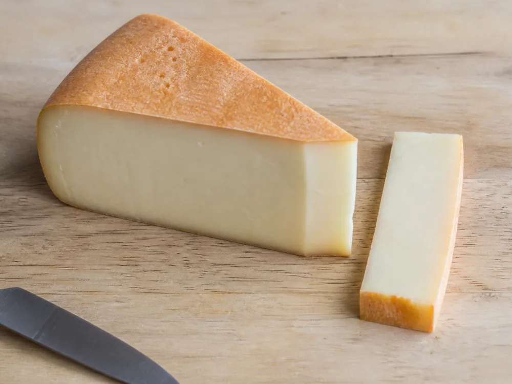Wedge with a thick strip of rind trimmed away and set beside it - Trappiste de Bricquebec | KnowTheCheese
